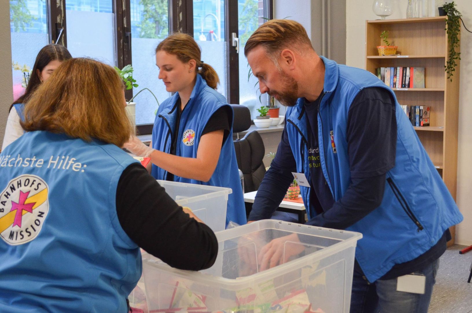 Drei DIN-Mitarbeiter verpacken Essenspackete