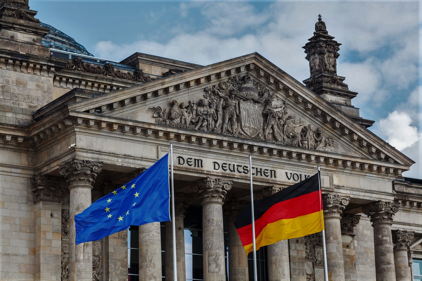 Bundestag. Im Vodergrund ist eine EU- und Deutschlandflagge