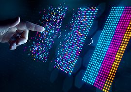 Eine Hand tippt auf quadratisch angeordnete bunte leuchtende Punkte