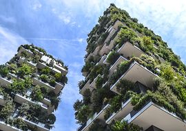 Zwei mit vielen grünen Pflanzen bepflanzte Hochhäuser vor blauem Himmel