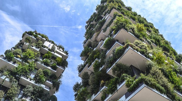Zwei mit vielen grünen Pflanzen bepflanzte Hochhäuser vor blauem Himmel