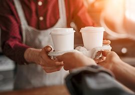Person hält Coffee To go in Mehrwegbechern 