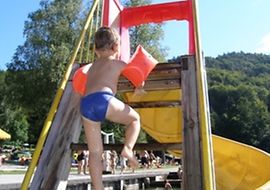 Kleinkind an einer Wasserrutsche im Freibad