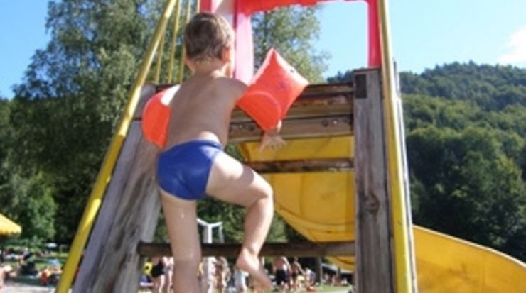 Kleinkind an einer Wasserrutsche im Freibad