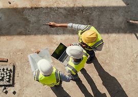 Ingenieur*innen begutachten Baupläne auf einer Baustelle