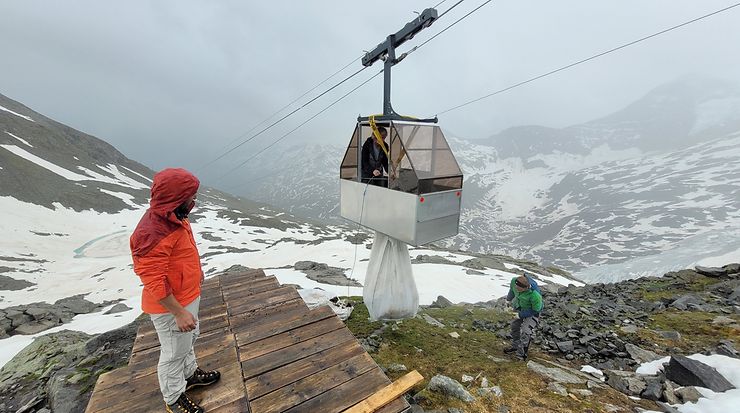 Personen bei der Beladung einer Materialseilbahn in verschneiter Berglandschaft
