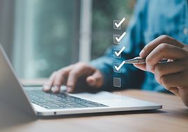 Person arbeitet am Laptop, hakt digitale Checkboxen ab; symbolisiert Planung und Organisation.