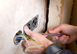 Elektroinstallateur montiert Steckdoese in Wand