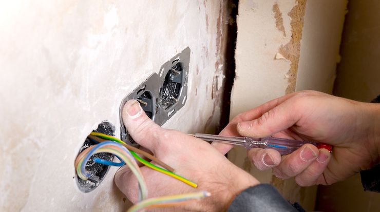 Elektroinstallateur montiert Steckdoese in Wand