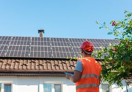 Mann in orangener Weste bewerten Solaranlage auf einem Dach