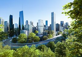 Moderne Stadt mit wolkenkratzenden Gebäuden, umgeben von Bäumen und grünen Landschaften.