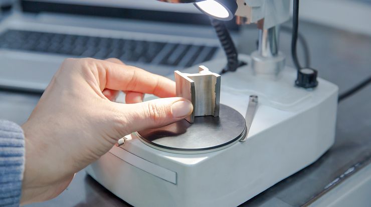 Ein Stück Metall in T-Trägerform wird unter ein Mikroskop platziert