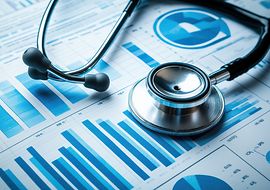 Silbernes Stethoskop liegt auf Blättern mit blauen Diagrammen und Statistiken.