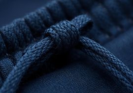 Nahaufnahme eines dunkelblauen Kordelzugs, geknotet auf Textilstoff