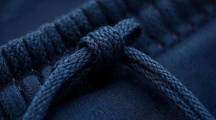 Nahaufnahme eines dunkelblauen Kordelzugs, geknotet auf Textilstoff