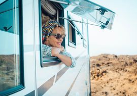 Frau schaut aus dem Fenster eines Caravans