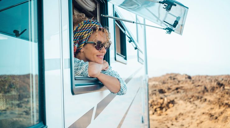 Frau schaut aus dem Fenster eines Caravans