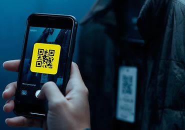 Hand scannt einen QR-Code auf dem Etikett einer blauen Jacke.