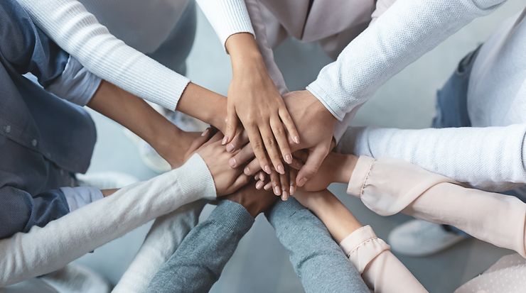 Personen eines Teams legen die Hände aufeinander