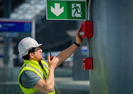 Techniker prüft eine Brandmeldeanlage in einer öffentlichen Einrichtung.