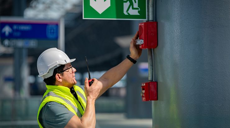 Techniker prüft eine Brandmeldeanlage in einer öffentlichen Einrichtung.