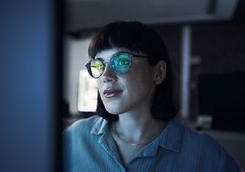 Frau, die auf ein Bildschirm schaut und in ihrer Brille spiegelt sich der Bildschirm