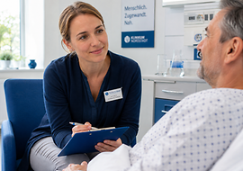 Eine Seelsorgerin unterhält sich in einem Krankenhaus mit einem Patienten