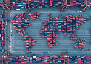 Vogelperspektive auf einen Containerhafen, die Container sind in Form der Kontinente angeordnet