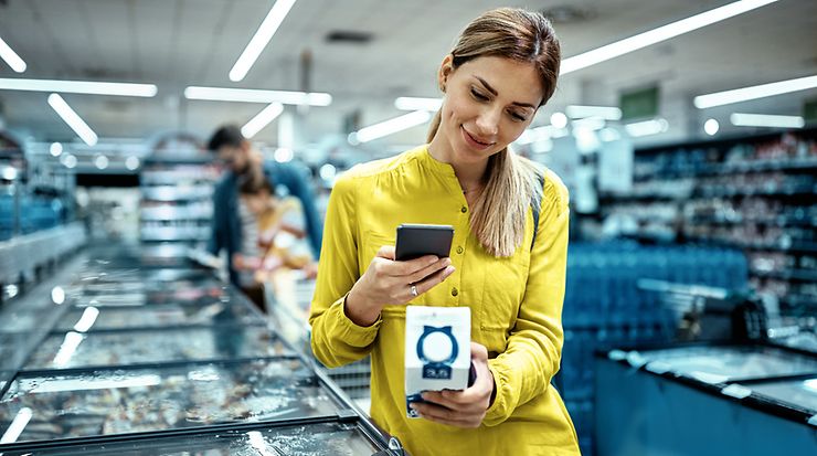 Frau scannt mit Smartphone ein Produkt in einem Geschäft