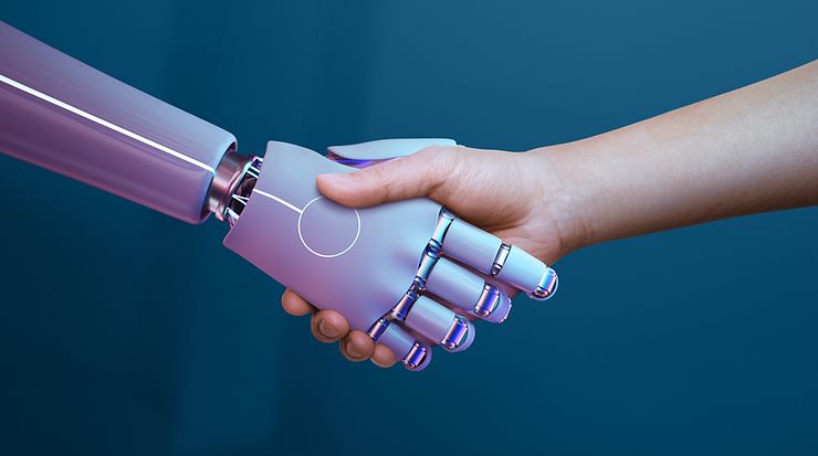 Ein menschlicher Arm schüttelt die Hand eines Roboterarms vor blauem Hintergrund