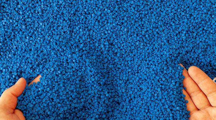 Blaue Kunststoffgranulate in zwei Händen.