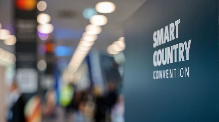 Im Vordergrund ein Schild mit der Aufschrift Smart Country Convention, im Hintergrund das Messegelände