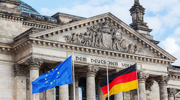 Bundestag. Im Vodergrund ist eine EU- und Deutschlandflagge