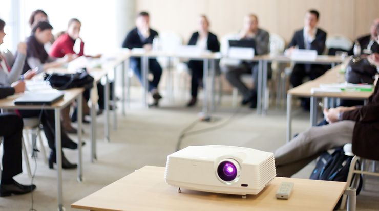 Menschen in einem Meetingraum mit Beamer