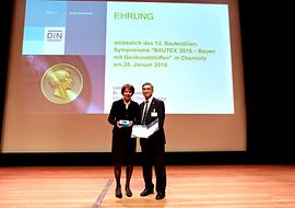 Frau Dr. Bohnsack, Mitglied der Geschäftsleitung bei DIN, übergibt die Beuth Denkmünze an Dr.-Ing. Matthias Mägel
