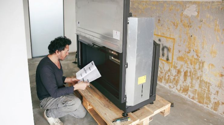 Person mit einer Gebrauchsanleitung beim Zusammenbau eines Kamins