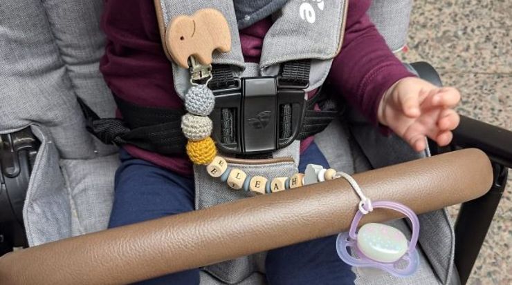 Baby mit Schnullerkette im Kinderwagen