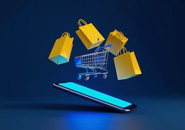 Schwebender Einkaufswagen und Einkaufstaschen über einem Smartphone als Symbolbild für E-Commerce.