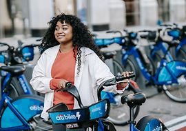 Frau mit Verleih-Fahrrad bei einem typischen städtischen Fahrradverleihpunkt