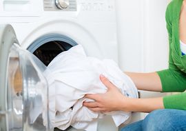 Frau bei der Entnahme von Wäsche aus einem Waschtrockner