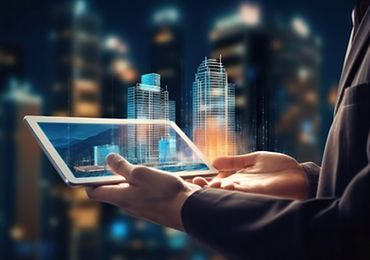 Eine Person hält ein Tablet, das digitale Gebäudemodelle in einer urbanen Nachtlandschaft anzeigt.